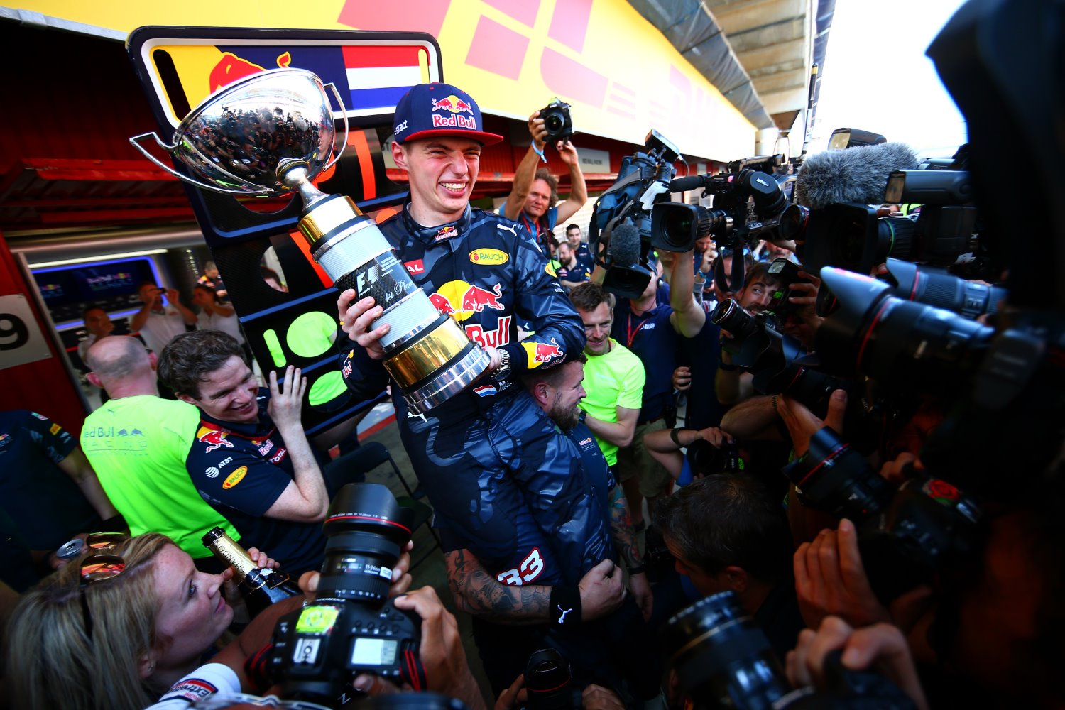 A happy Verstappen is surrounded by reporters