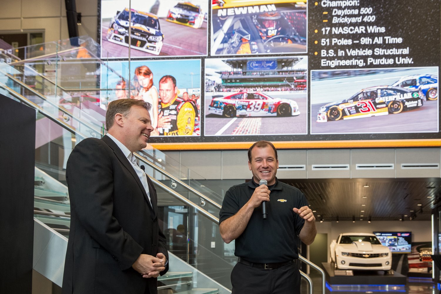 General Motors U.S. Vice President Performance Vehicles and Motorsports Jim Campbell (left) looks on as Team Chevy NASCAR driver Ryan Newman addresses the gathering at the opening of the new Powertrain Performance and Racing Center 