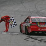 Kyle Busch, driver of the #18 Skittles Toyota, celebrates with the checkered flag after winning