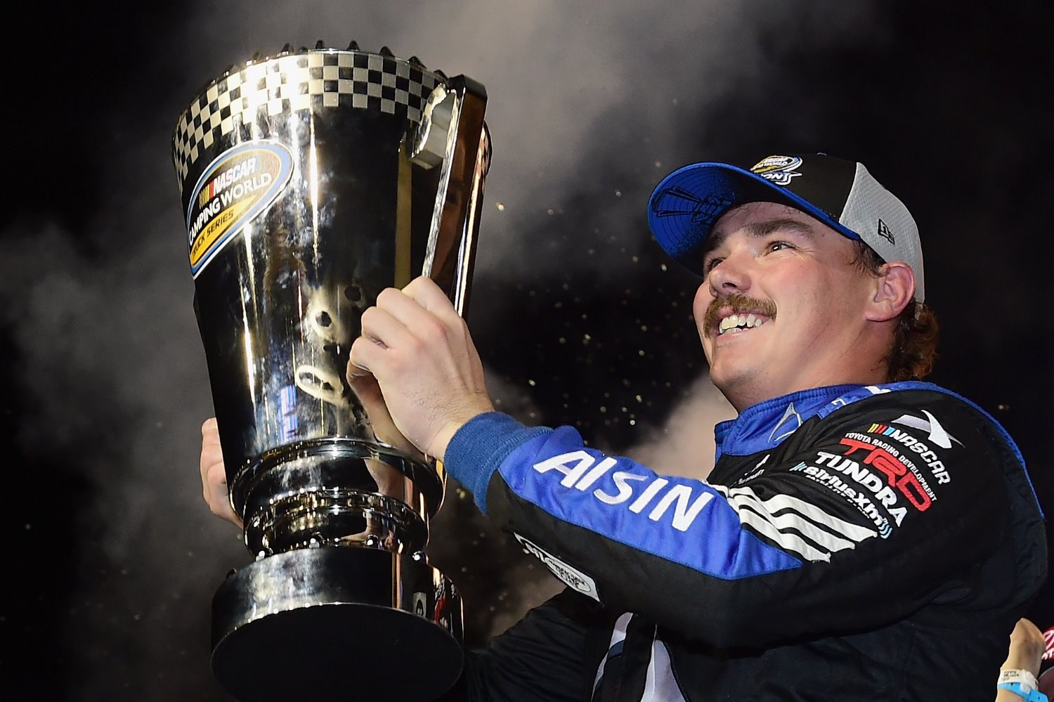 rett Moffitt, driver of the #16 AISIN Group Toyota, celebrates in victory lane with the trophy after winning the NASCAR Camping World Truck Series Ford EcoBoost 200 and the NCWTS Championship