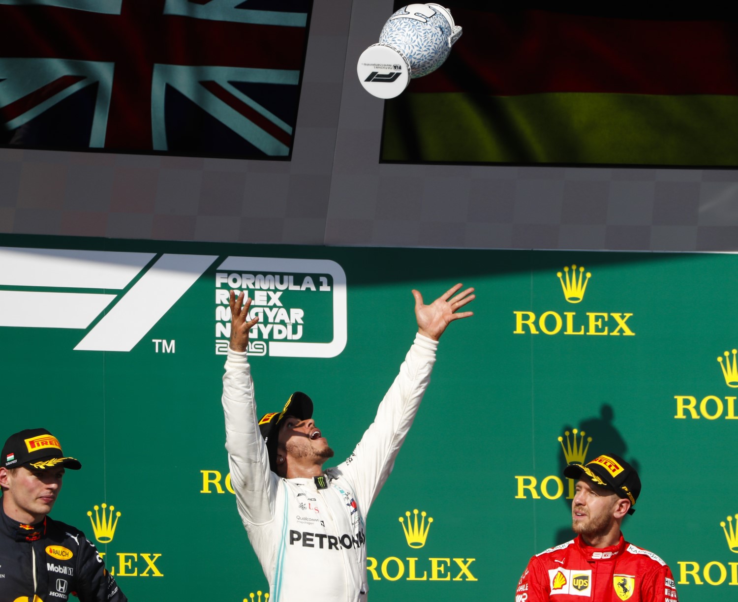 Losers Verstappen and Vettel watch winner Hamilton toss his winning trophy in the air