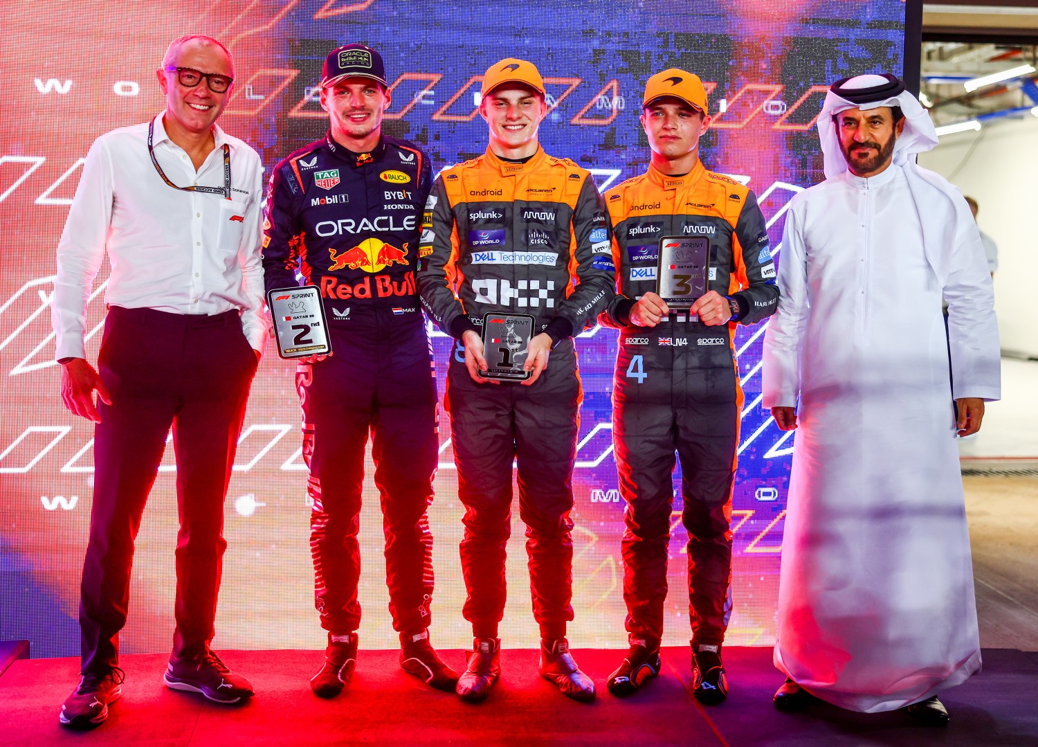 Sprint winner Oscar Piastri of Australia and McLaren, 2nd placed Max Verstappen of the Netherlands and Oracle Red Bull Racing and third placed Lando Norris of Great Britain and McLaren pose for a photo with their trophies and Stefano Domenicali, CEO of the Formula One Group, and Mohammed ben Sulayem, FIA President, in parc ferme after the Sprint ahead of the F1 Grand Prix of Qatar at Lusail International Circuit on October 07, 2023 in Lusail City, Qatar. (Photo by Mark Thompson/Getty Images) // Getty Images / Red Bull Content Pool