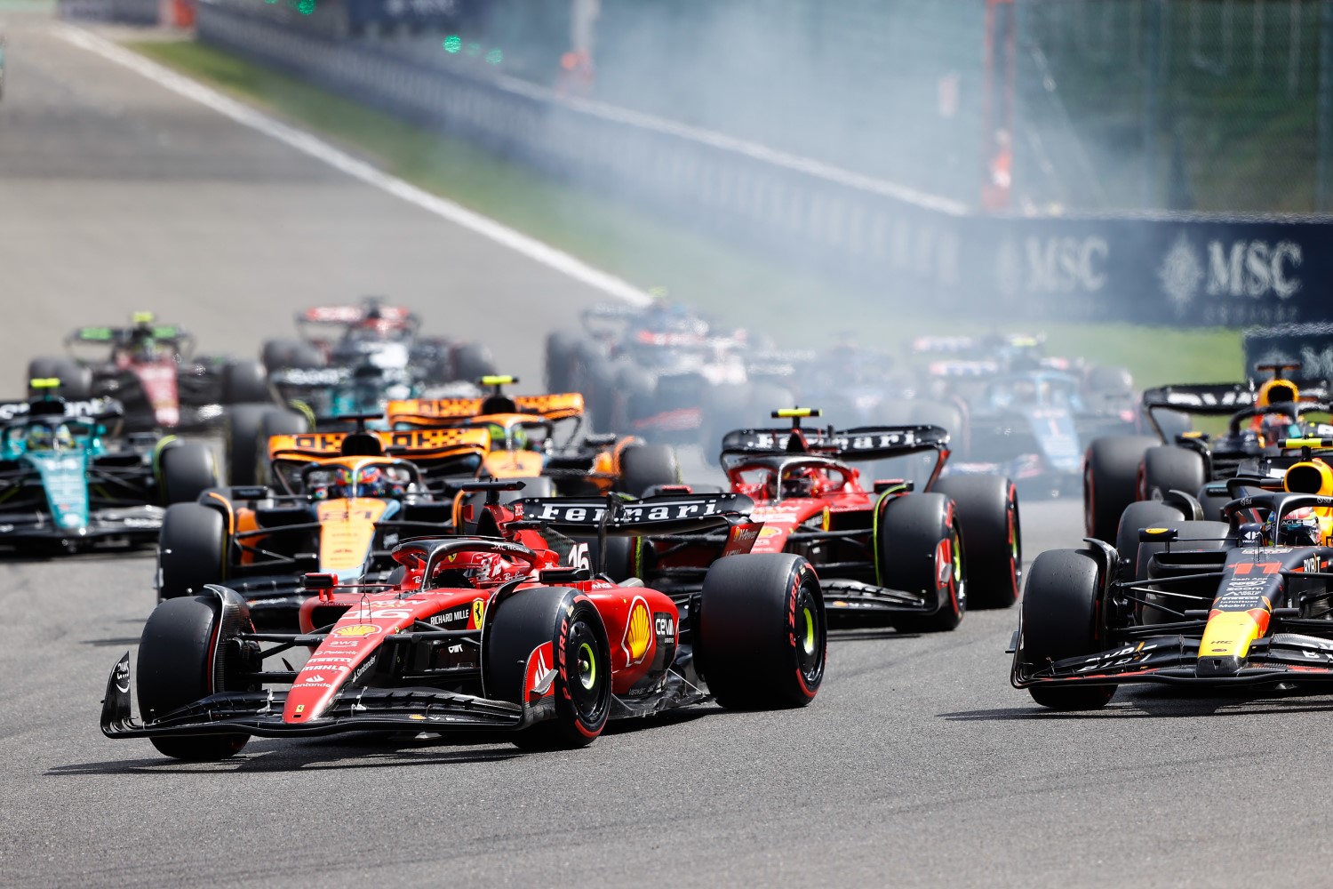 Charles Leclerc, Ferrari SF-23, leads Sergio Perez, Red Bull Racing RB19, Carlos Sainz, Ferrari SF-23, Oscar Piastri, McLaren MCL60, and the rest of the field at the start during the Belgian GP at Circuit de Spa Francorchamps on Sunday July 30, 2023 in Spa, Belgium. (Photo by Andy Hone / LAT Images)